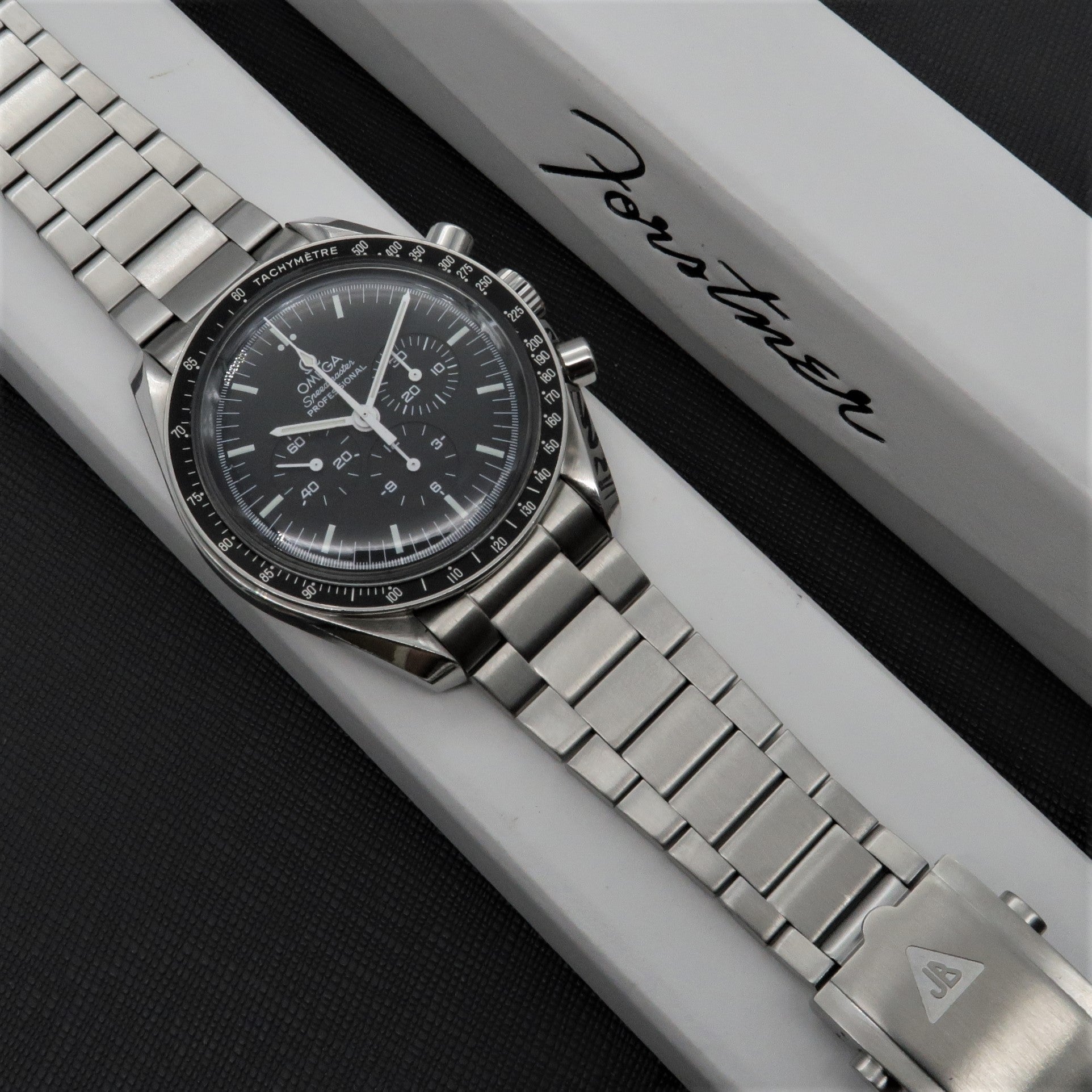 Omega Speedmaster chronograph watch with stainless steel flat link bracelet on white display box