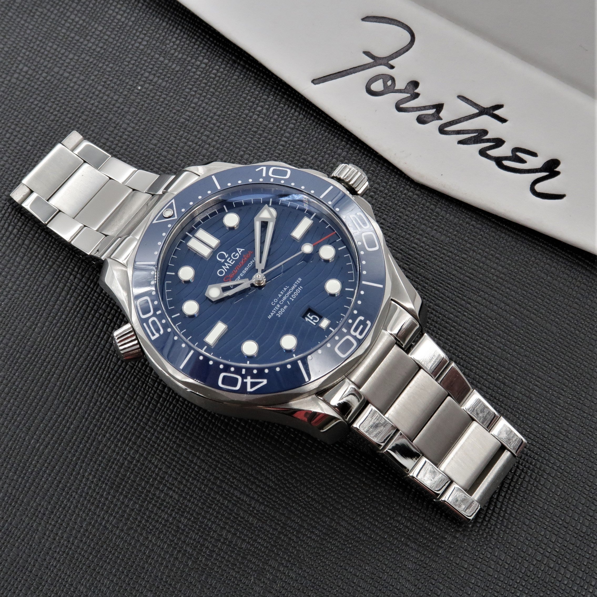 Omega Seamaster dive watch with blue dial and stainless steel bracelet on dark textured surface