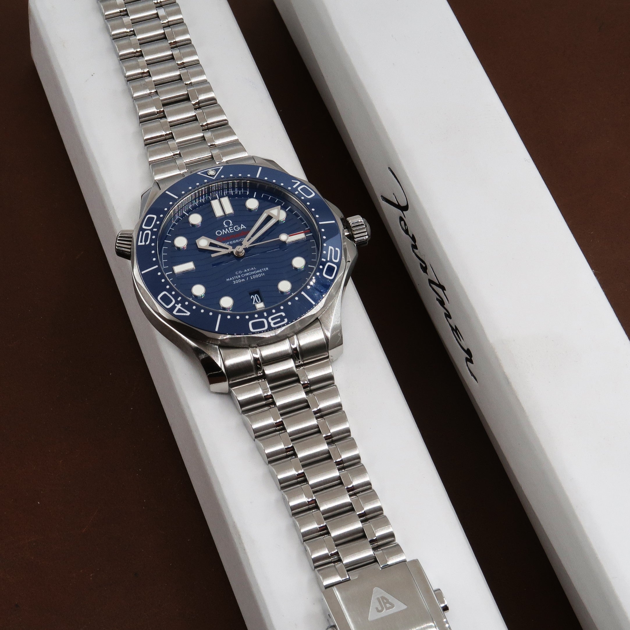 Omega Seamaster Professional 300M dive watch with blue dial and steel bracelet displayed on white presentation box with Forstner branding