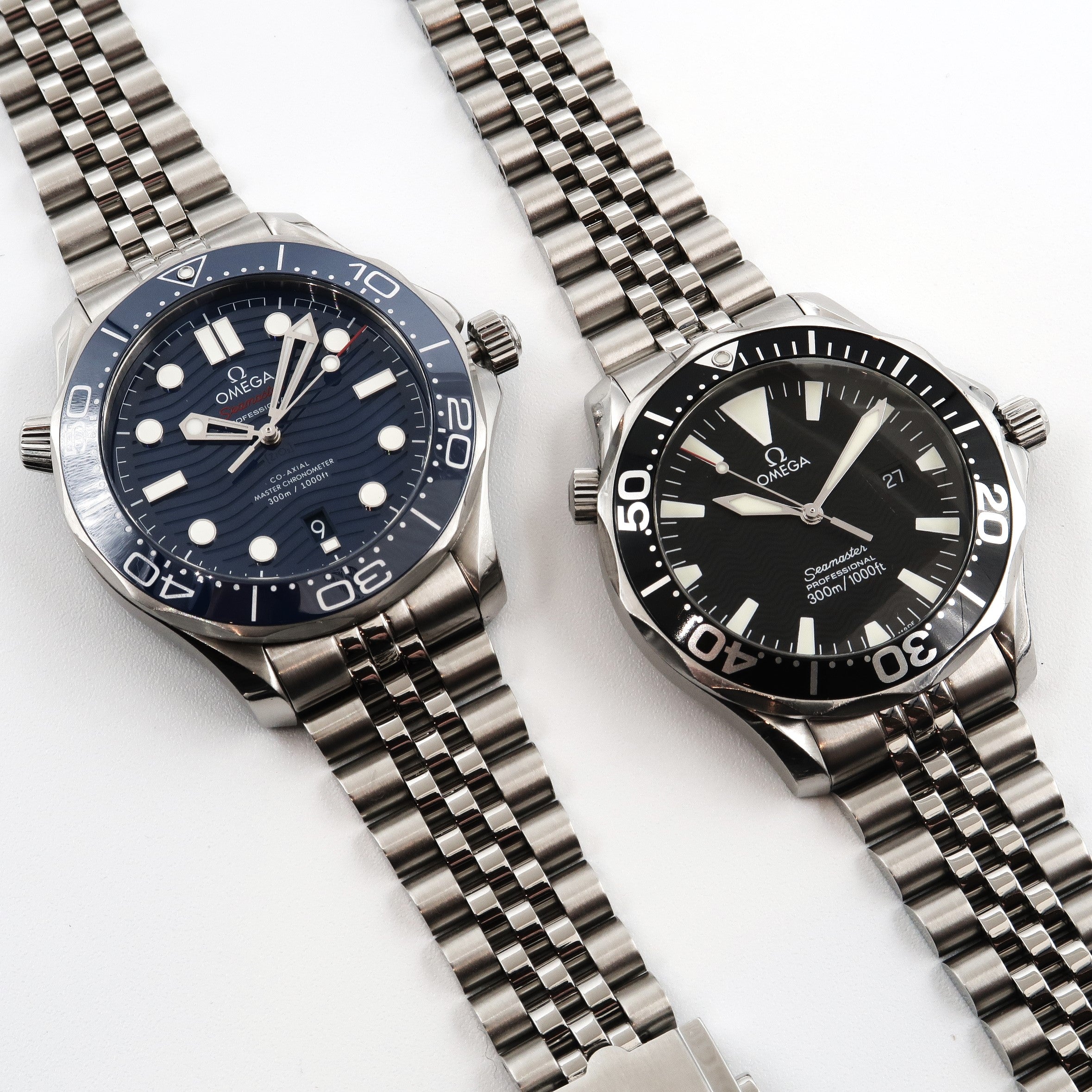 Two Omega Seamaster Professional 300M diver watches with stainless steel bracelets and blue and black dials on white background