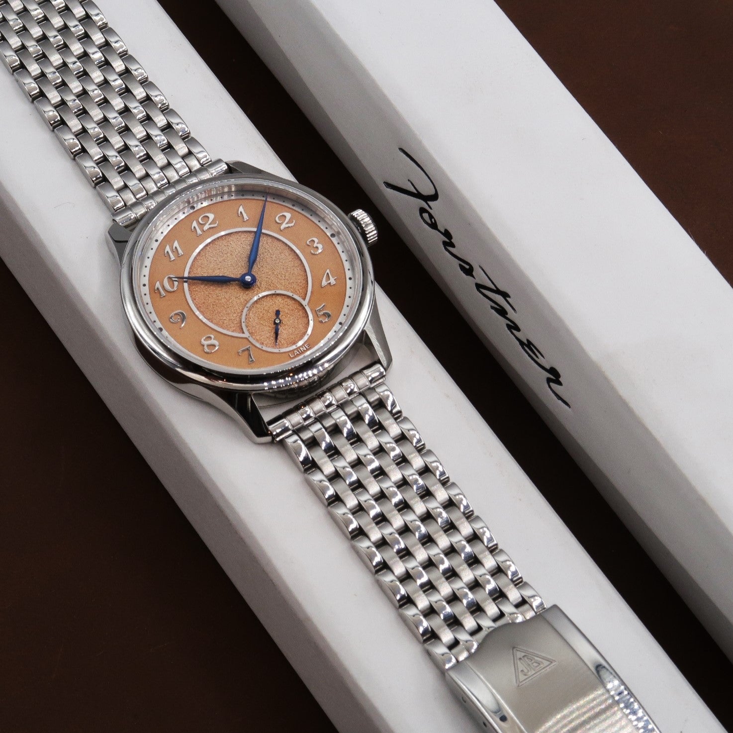 Stainless steel watch with copper dial and sub-dial on beads of rice bracelet, displayed on white branded box