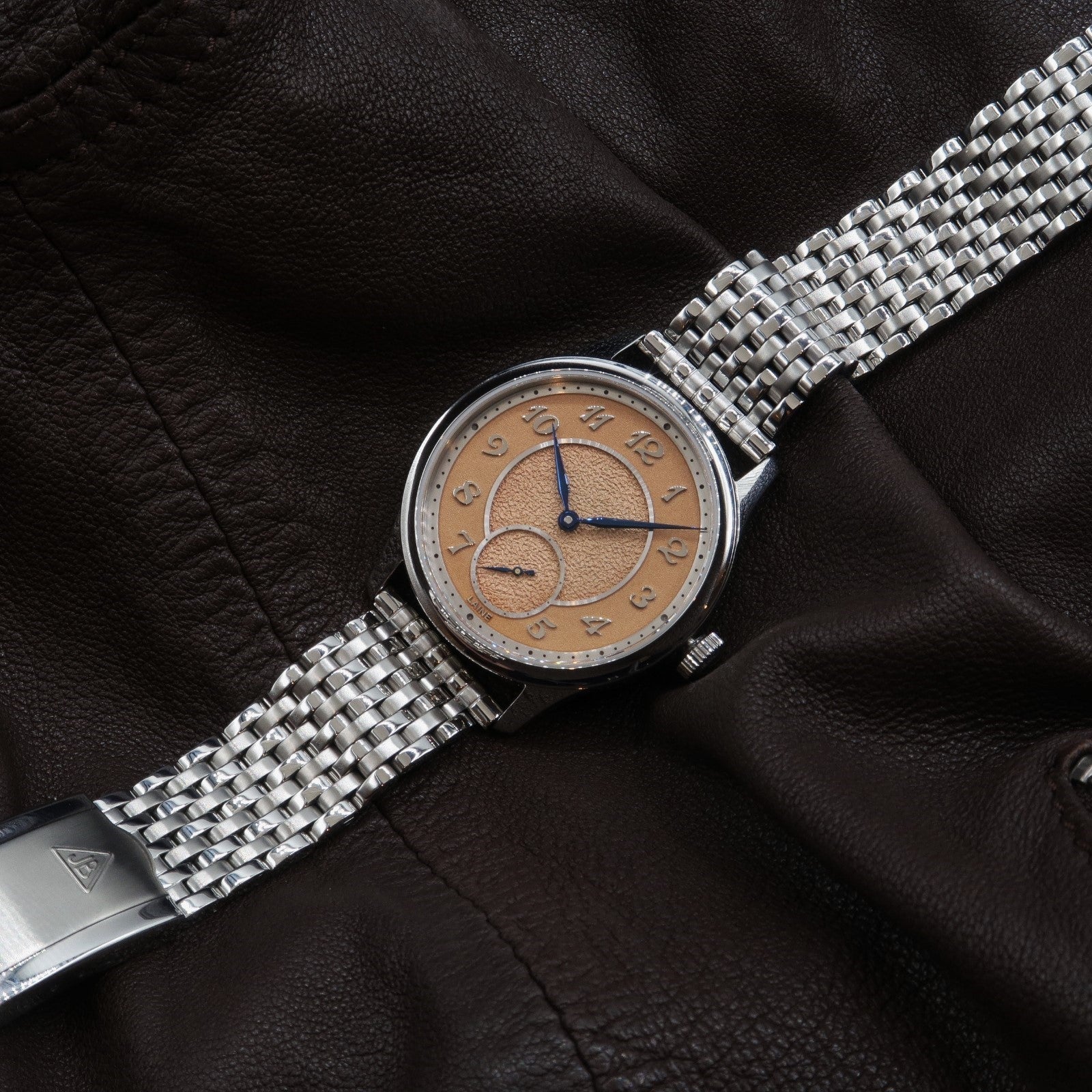 Stainless steel beads of rice watch bracelet with polished metal links on luxury leather background