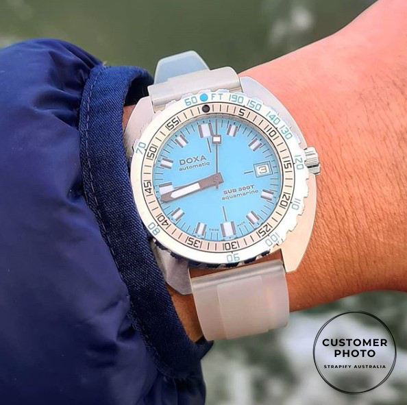 Doxa Sub 300 automatic dive watch with light blue dial, white rubber strap, rotating bezel worn on wrist with navy jacket