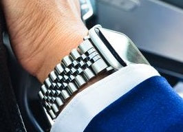 Apple Watch Jubilee bracelet in silver with two-tone metal links worn on wrist with blue sleeve