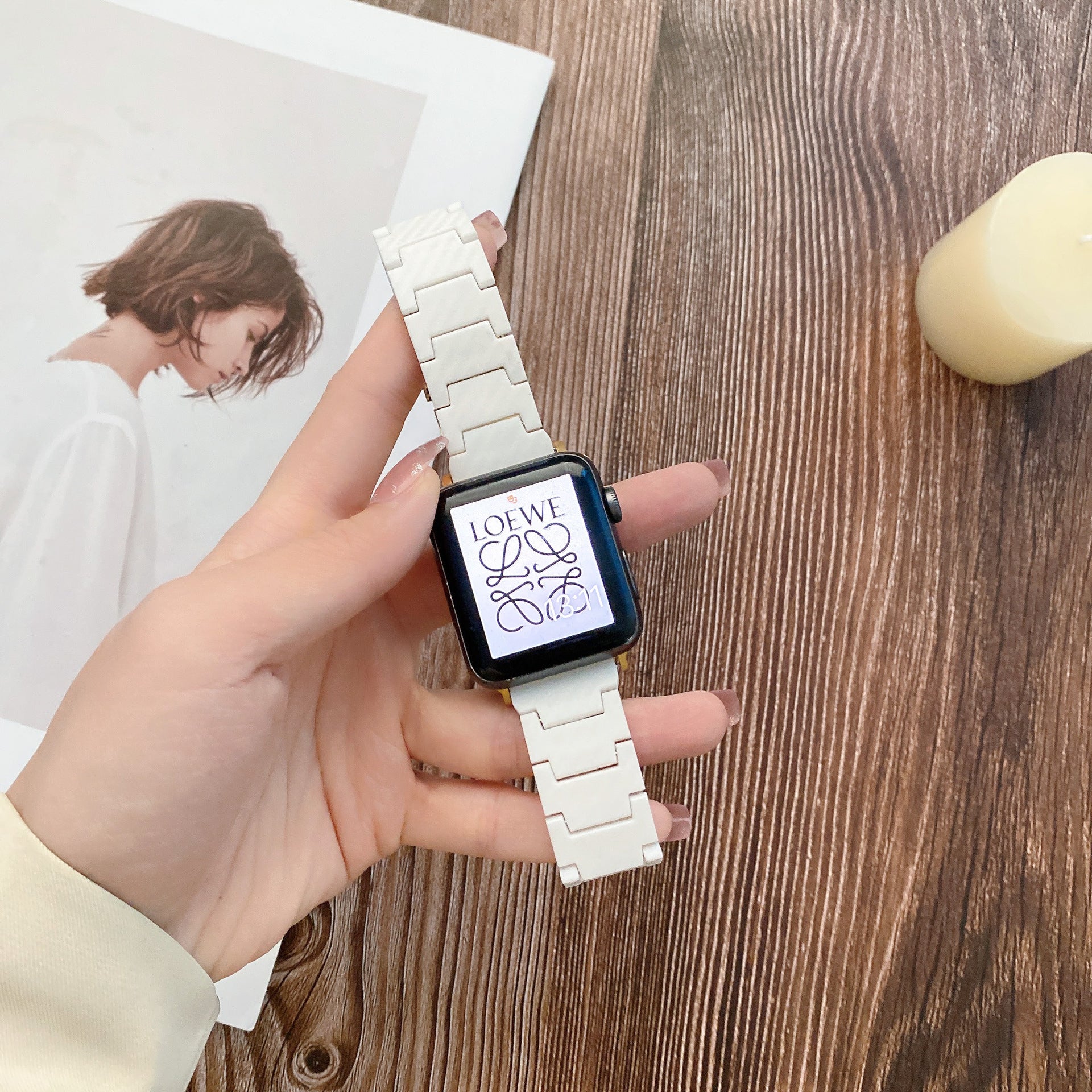 Luxury smartwatch with white ceramic link bracelet and black case displaying designer logo on screen, held in hand