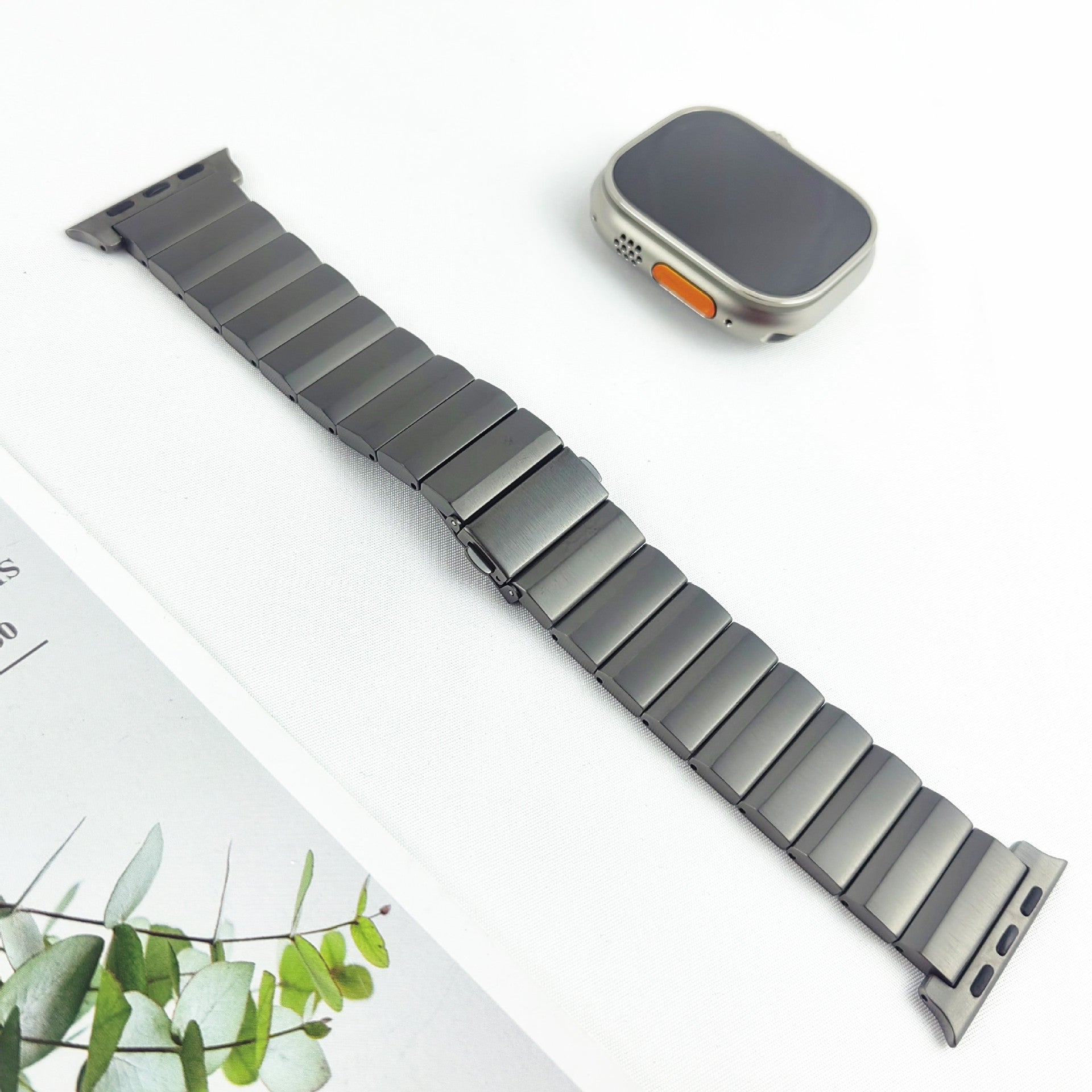 Titanium link bracelet band for Apple Watch with silver metal segments and matching smartwatch with orange accent button