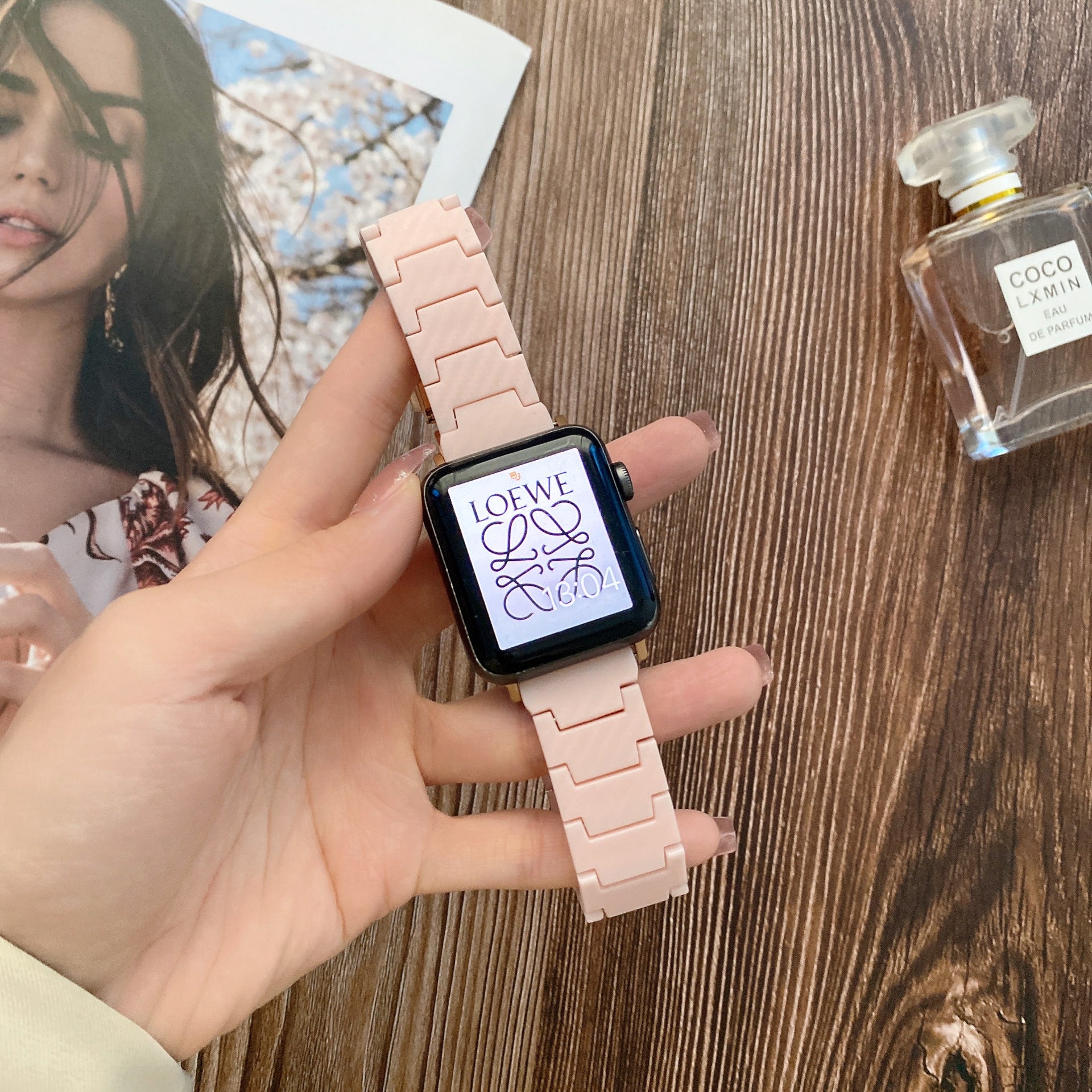 Pink ceramic link bracelet for Apple Watch with Loewe logo display on smartwatch face