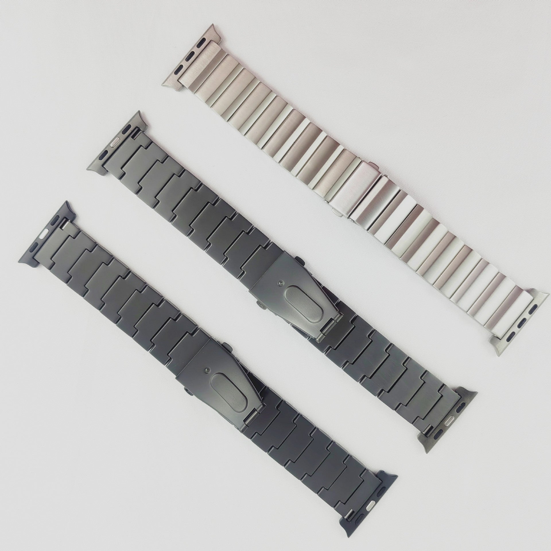 Titanium smartwatch bands in silver, gray, and black with metal link bracelets and connector lugs