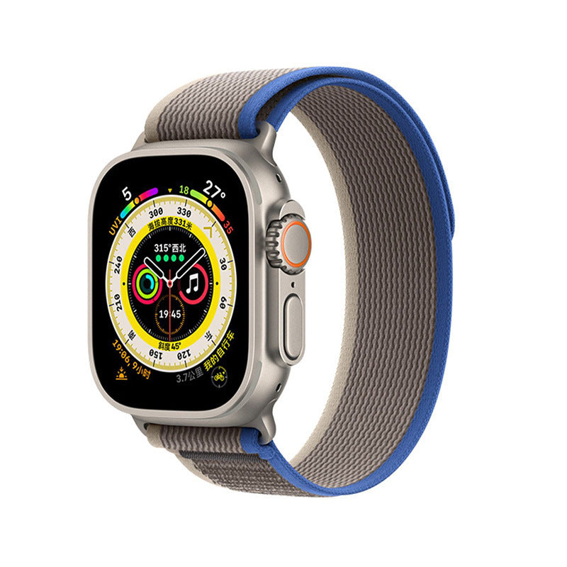 Apple Watch Ultra with gray and blue Trail Loop band showing compass dial face and fitness tracking features