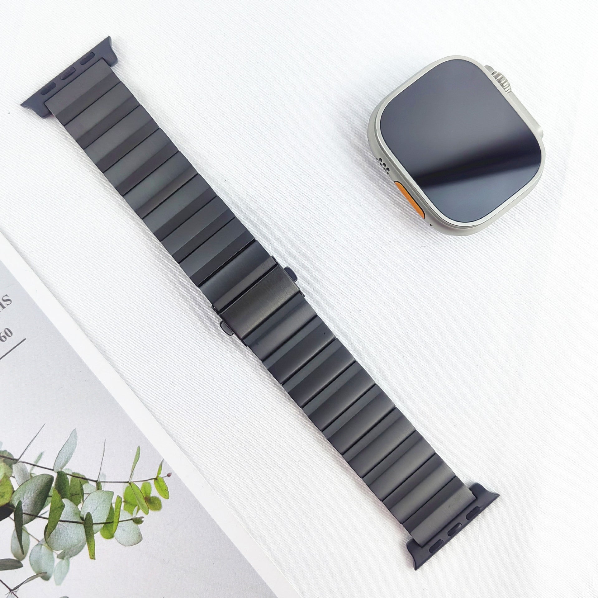 Titanium smartwatch with black magnetic link bracelet and silver square case displayed on white background with plant decoration