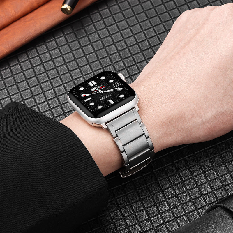 Silver titanium bracelet smartwatch on wrist with black dial and stainless steel link band, lifestyle photo on textured surface