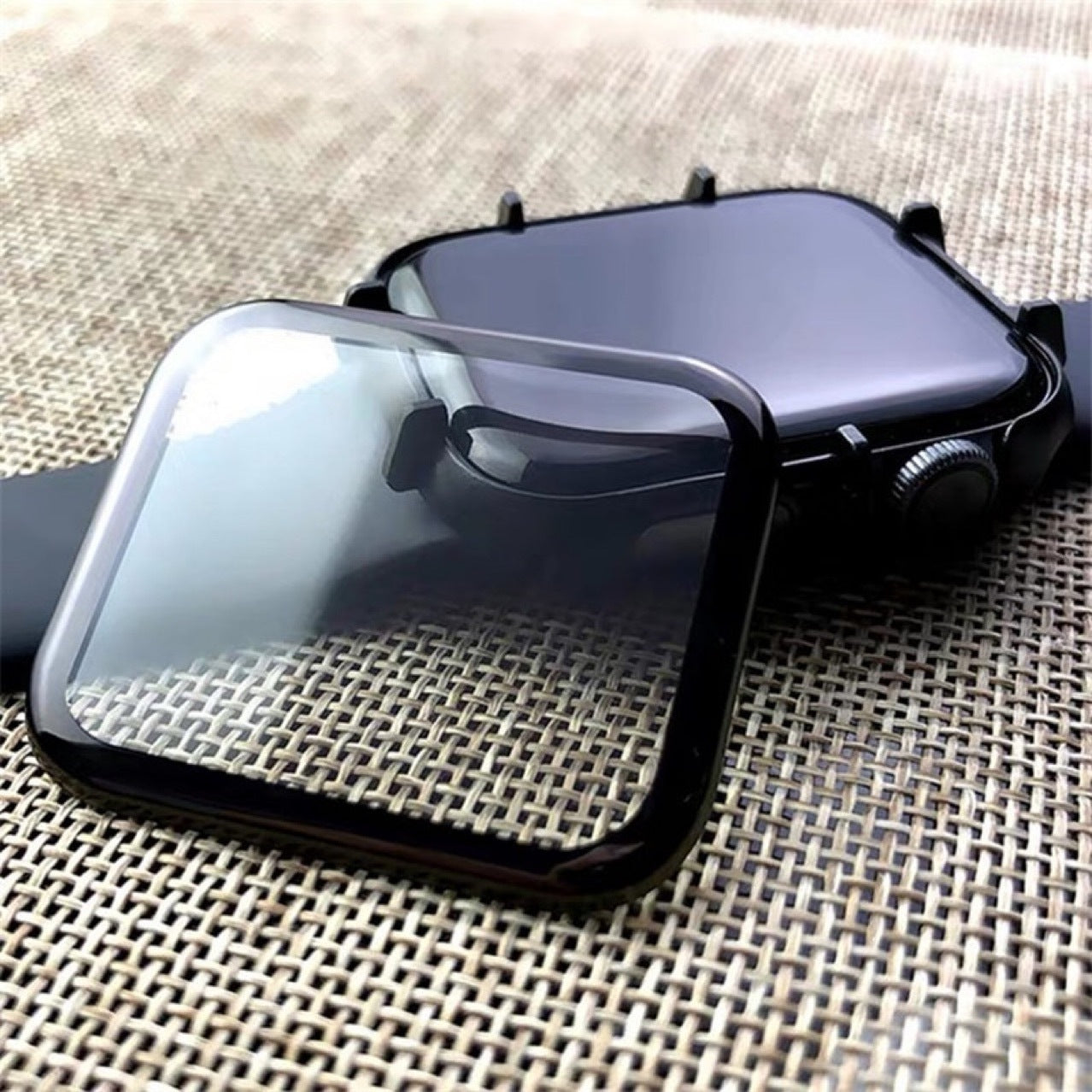 Protective screen protector case for smartwatch with clear glass front and black bumper frame on textured surface