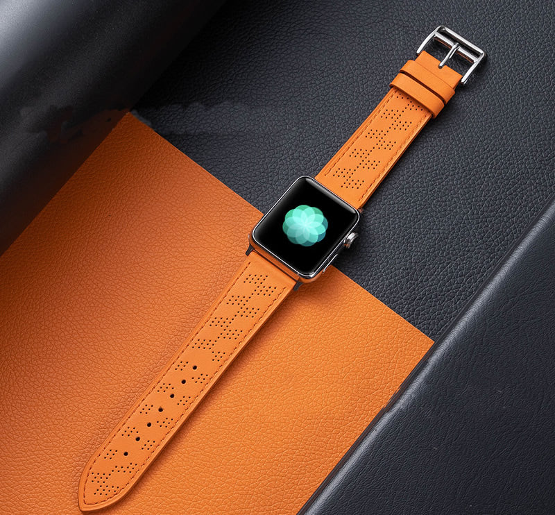 Apple Watch with orange perforated leather single tour band on gray and orange textured background