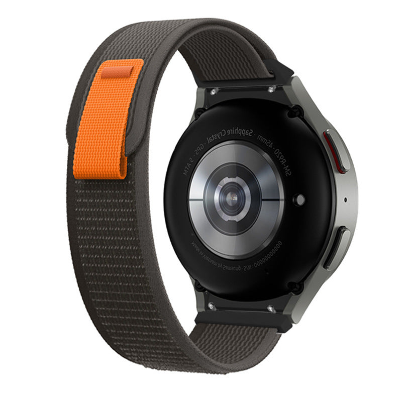 Samsung Galaxy Watch 4 smartwatch with gray and orange trail loop sport band, circular AMOLED display, and side button