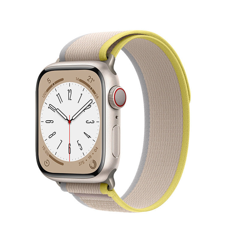 Silver aluminum Apple Watch with white dial and yellow Trail Loop band, featuring red digital crown and fitness tracking display