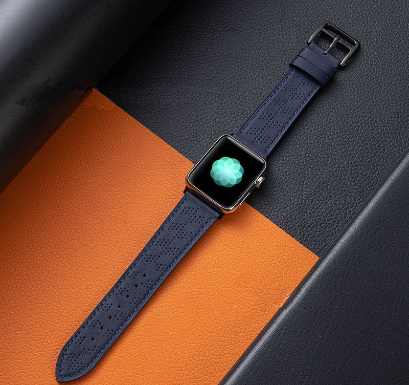 Apple Watch with navy blue perforated single tour band on orange and gray leather background