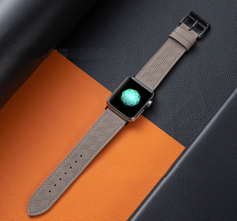 Apple Watch with grey perforated leather single tour band on orange and grey textured background