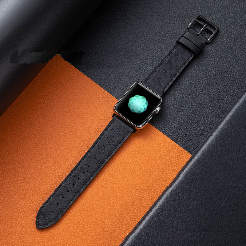 Apple Watch with black perforated single tour band on orange and gray leather background