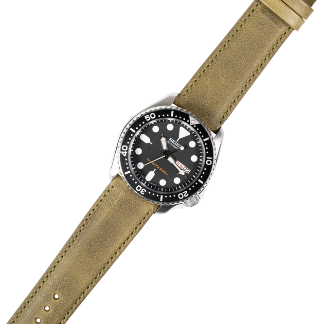 Dive watch with black dial and bezel on olive green padded leather quick release strap