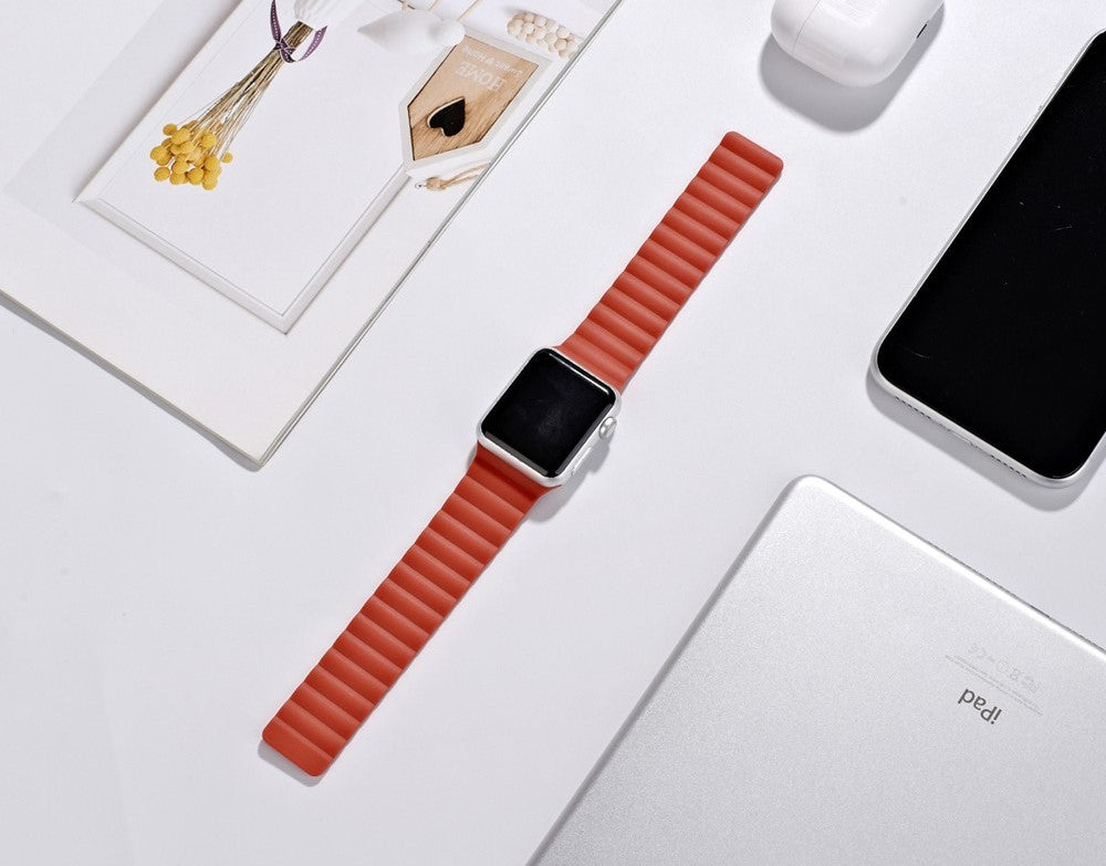Apple Watch magnetic silicone loop band in red with silver case on white surface