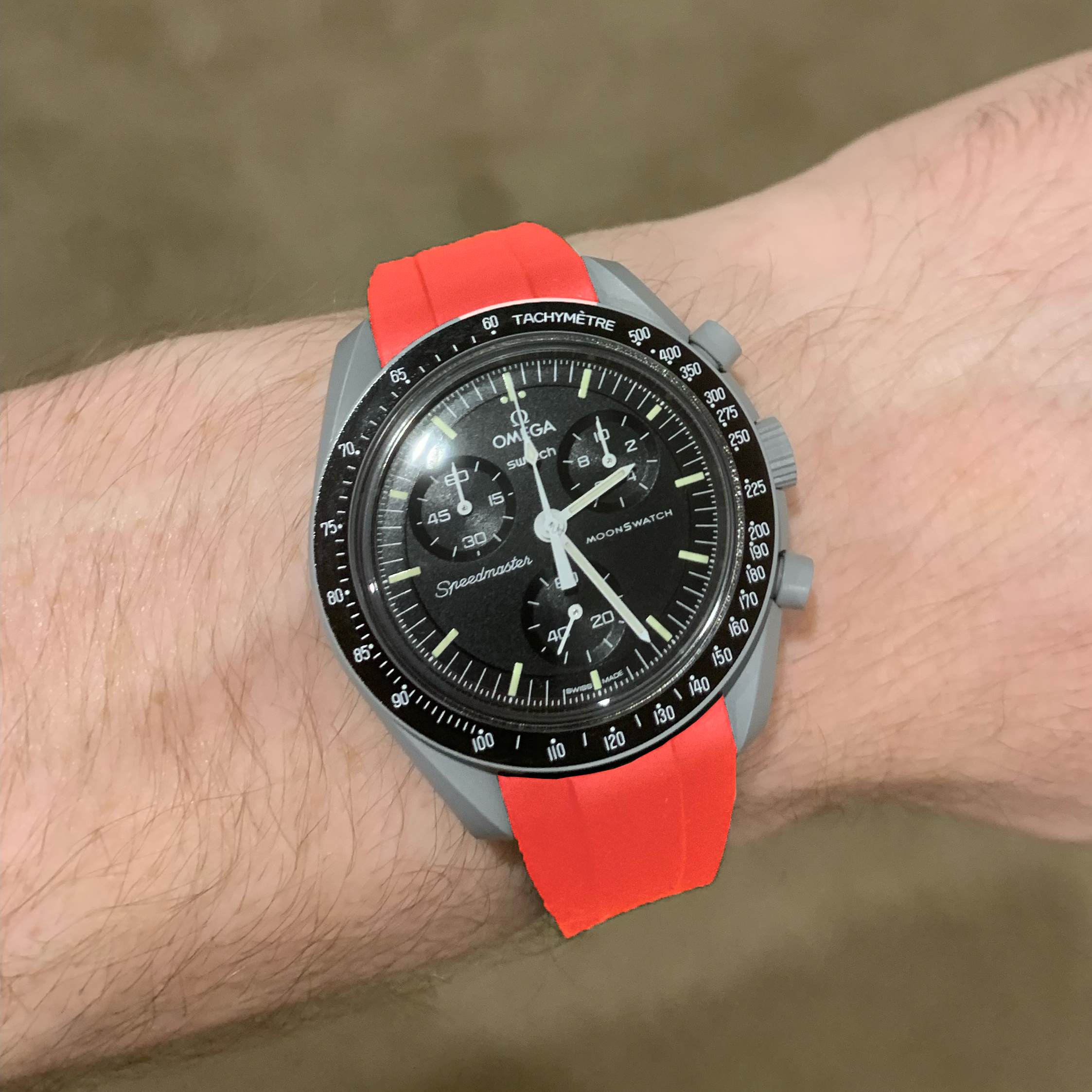 Omega MoonSwatch Speedmaster chronograph watch with black dial, red rubber strap, and tachymetre bezel on wrist