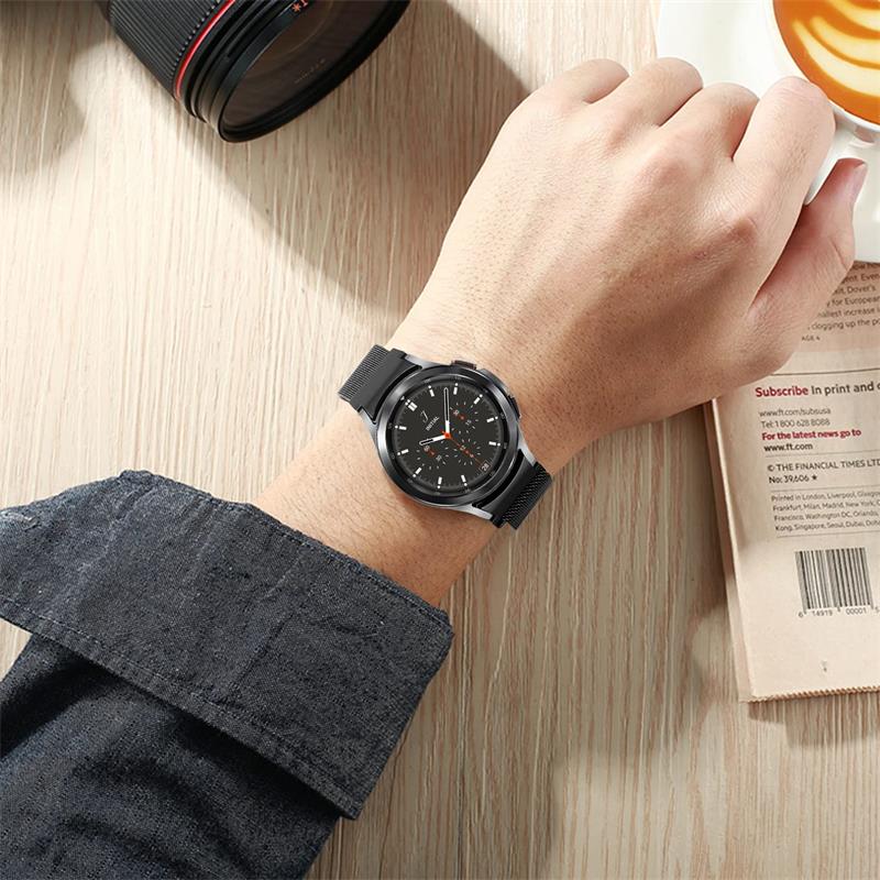 Man wearing black Galaxy smartwatch with Milanese mesh band on wrist, lifestyle shot on wooden desk
