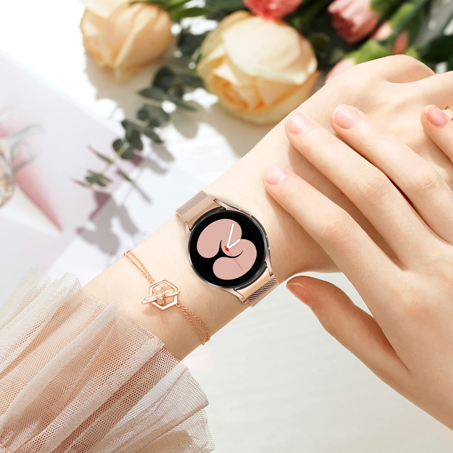 Woman wearing champagne gold Milanese loop smartwatch with black dial face and pink floral design on wrist