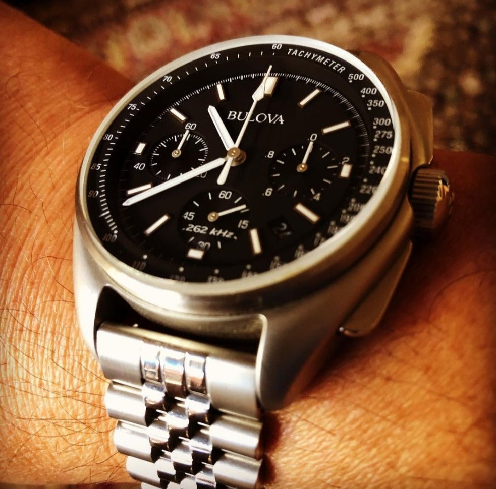 Bulova chronograph watch with black dial and silver stainless steel jubilee bracelet on wrist
