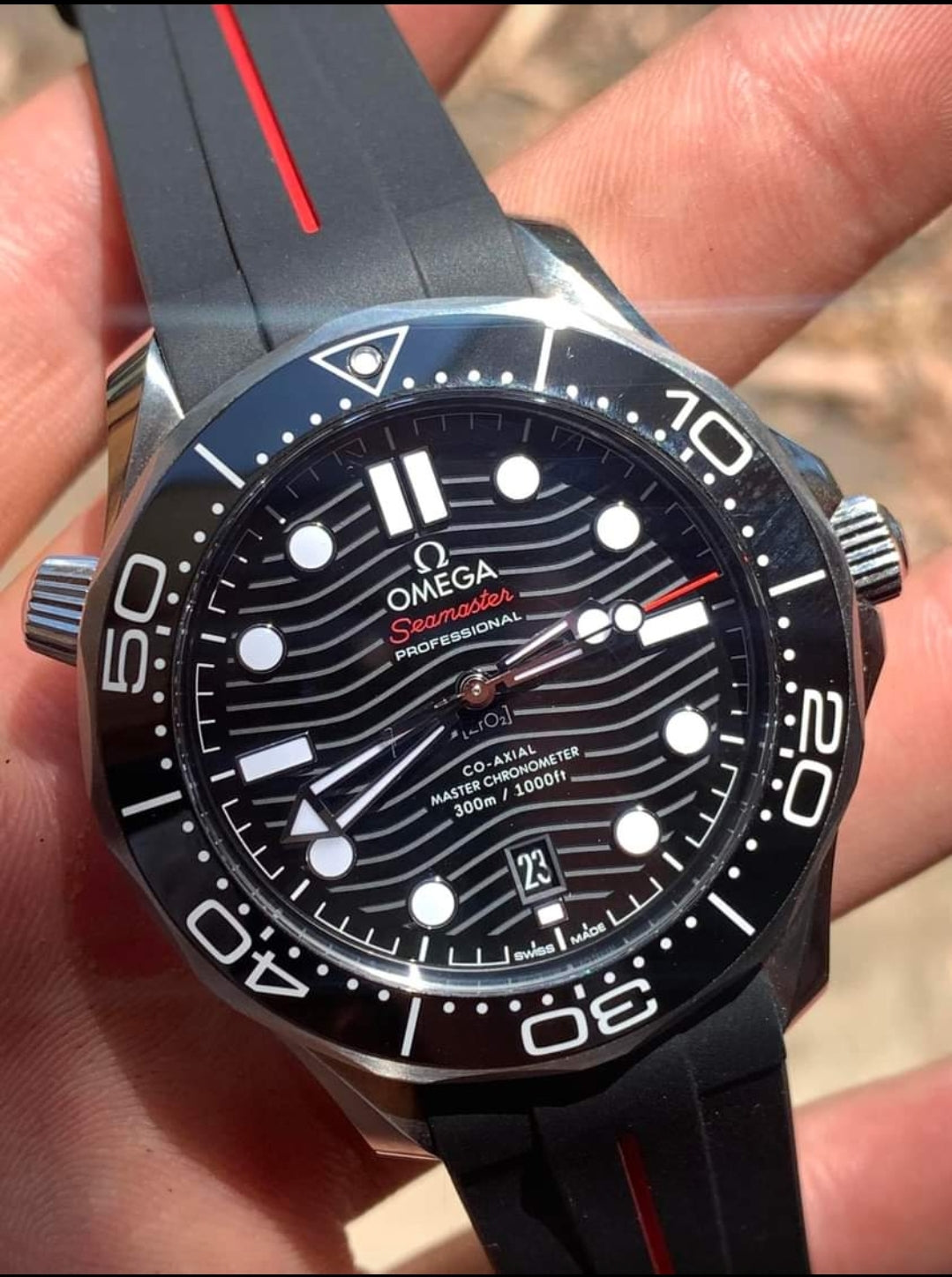 Omega Seamaster Professional diving watch with black dial, wave pattern, white markers, and red accents on rubber strap