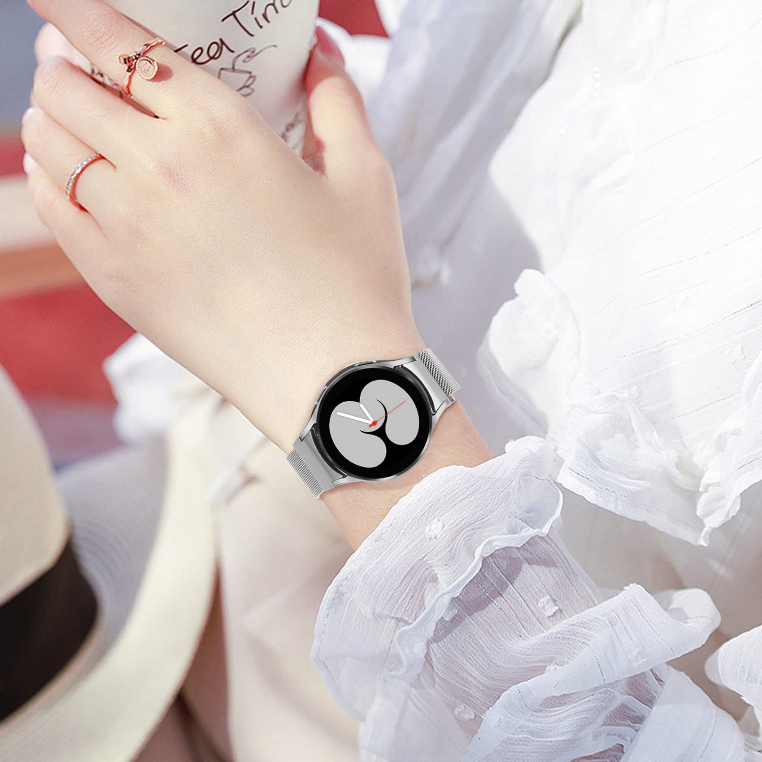 Woman wearing silver Milanese mesh band smartwatch with black dial and red accents on wrist