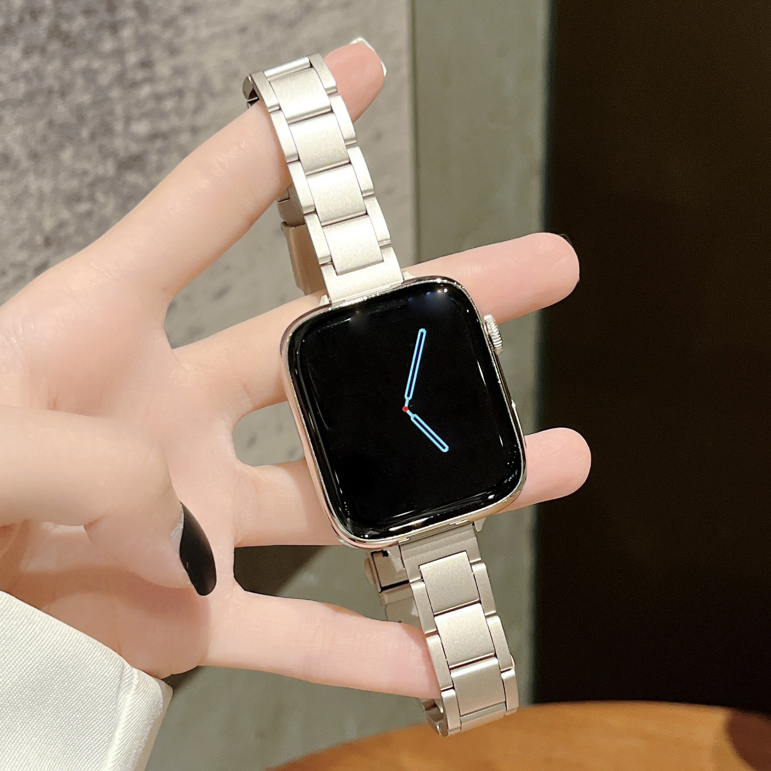 Silver stainless steel bracelet band for smartwatch with square black display showing time, held in hand