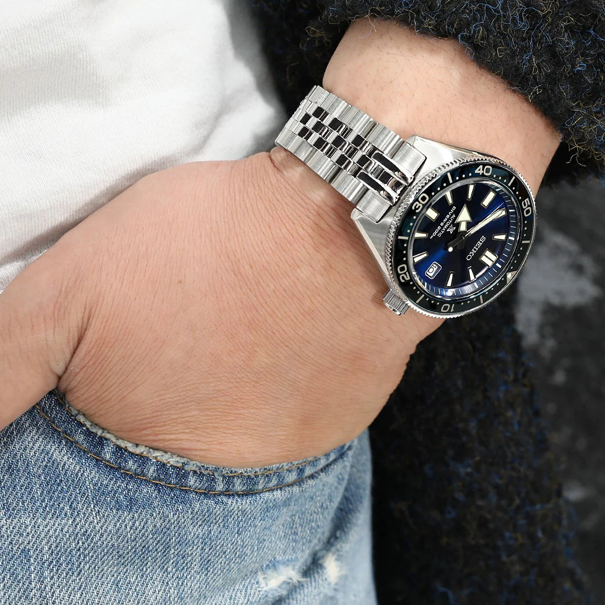 Men's wrist wearing Seiko diver watch with stainless steel Super-J Louis jubilee bracelet and blue dial