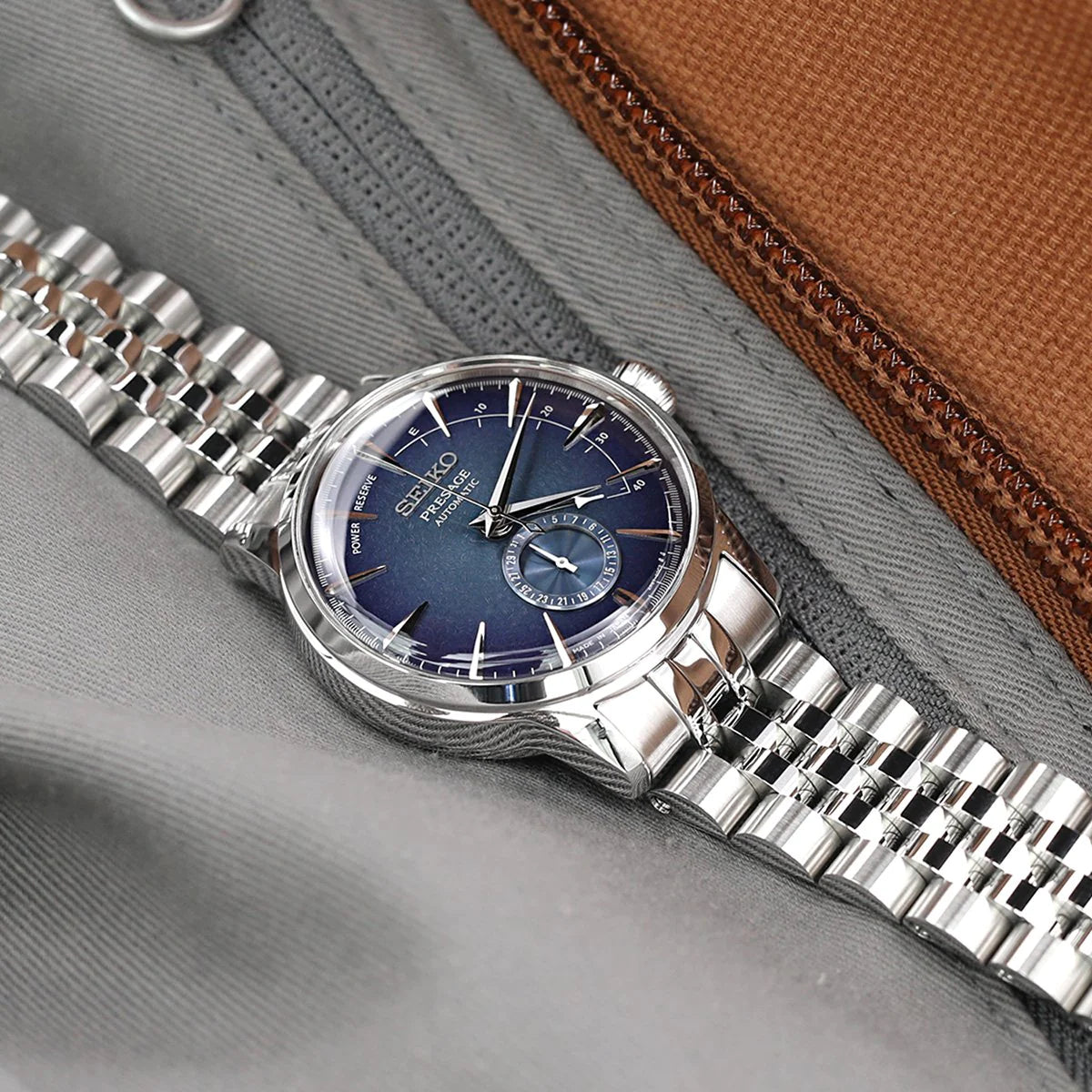 Seiko Cocktail SSA345 watch with Strapcode Angus-J Louis JUB stainless steel bracelet and blue dial on gray fabric background