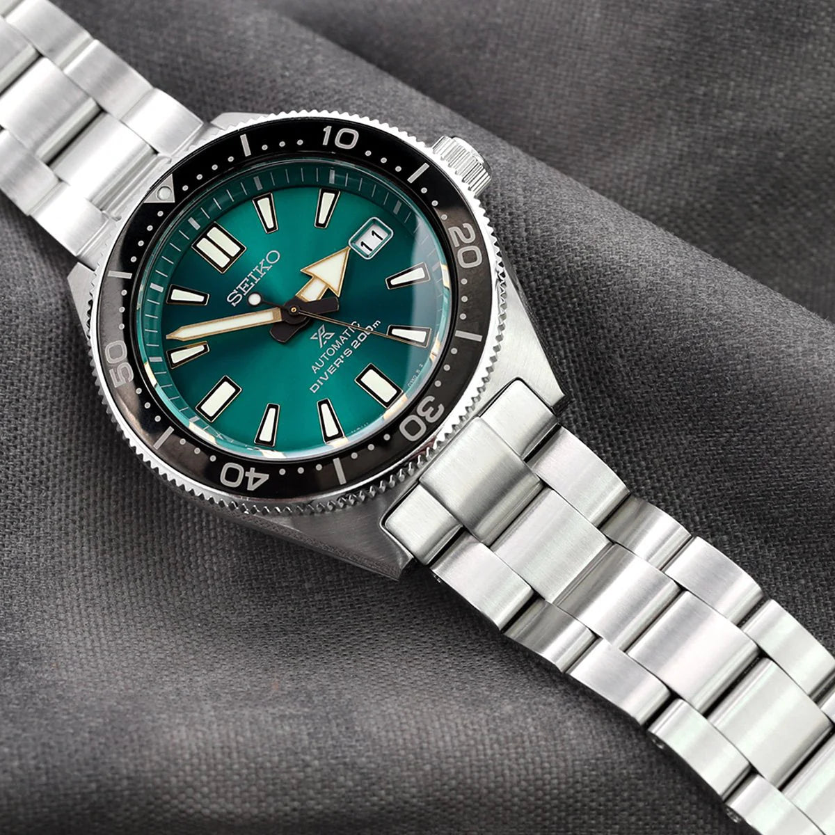 Seiko SBDC053 62MAS watch with turquoise dial, stainless steel bracelet and black bezel on gray fabric background