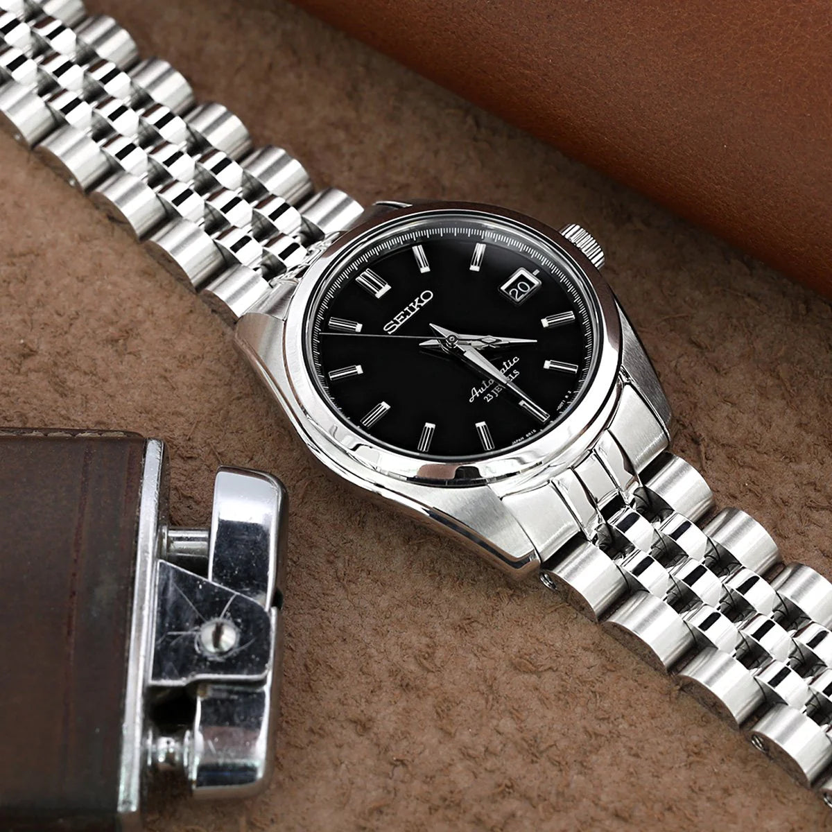 Seiko SARB033 watch with stainless steel Angus-J Jub Louis bracelet and date window on brown leather background
