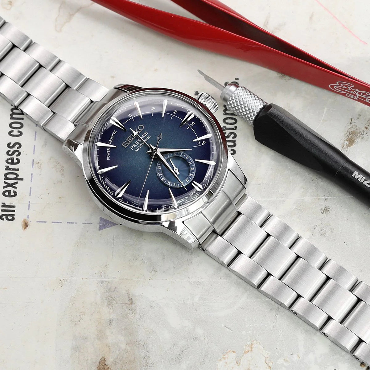 Seiko Presage cocktail watch with dark blue dial and stainless steel Super-O Boyer bracelet on marble background