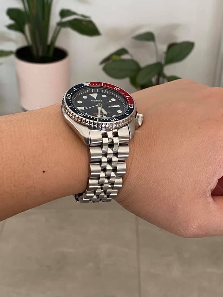 Seiko dive watch with red and black bezel on stainless steel jubilee bracelet worn on wrist