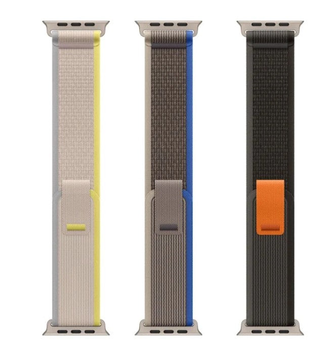 Three Apple Watch Trail Loop bands in yellow, blue, and orange woven fabric styles with adjustable closures