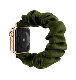 Olive green velvet scrunchie with rose gold Apple Watch attachment, coiled on white background