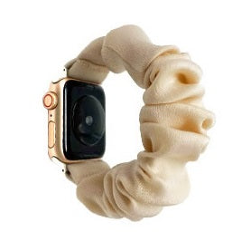 Gold Apple Watch with cream-colored fabric scrunchie loop band attached