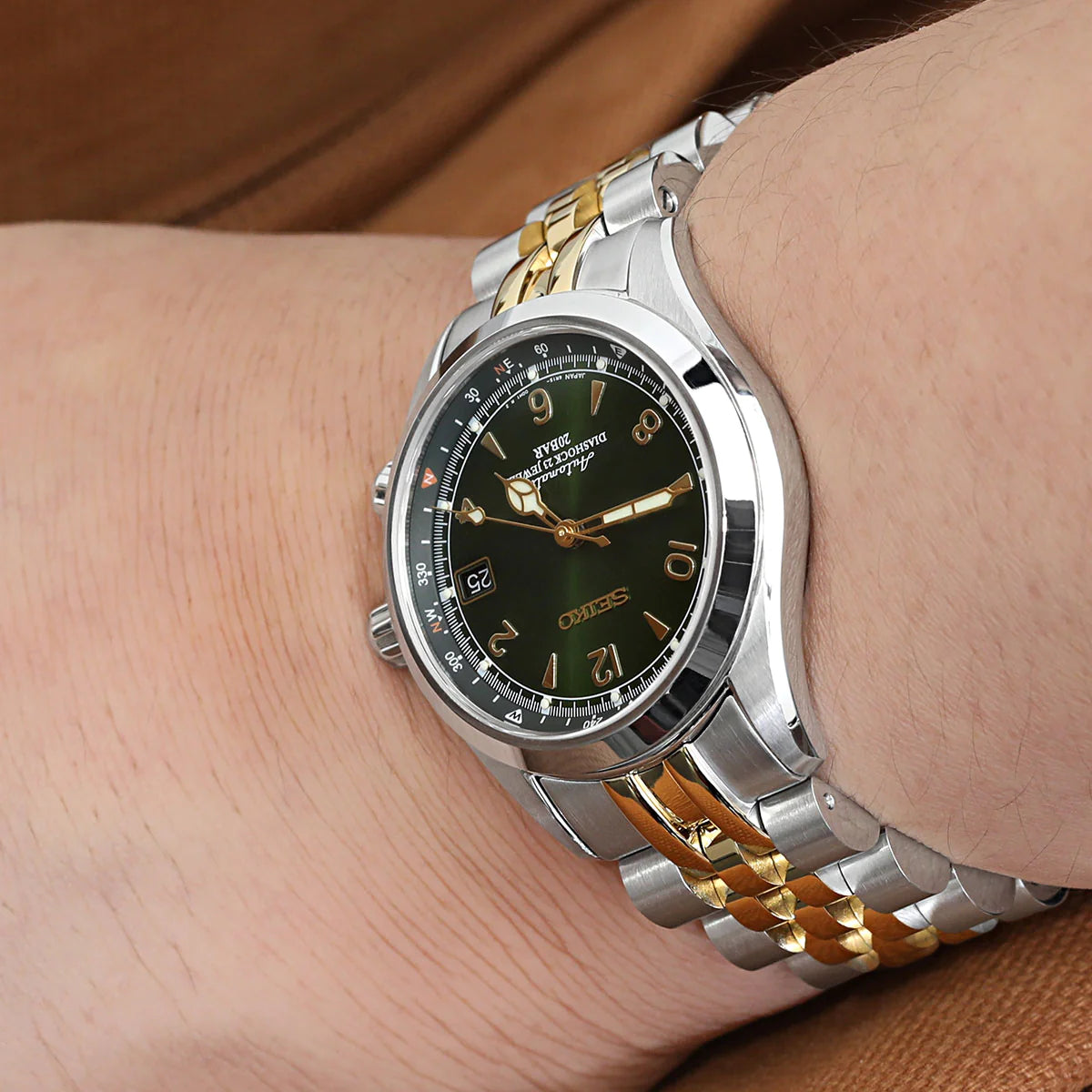 Two-tone silver and gold stainless steel watch bracelet with solid end links on wrist, featuring curved lugs and polished finish for Seiko Alpinist and Hamilton Khaki Field watches