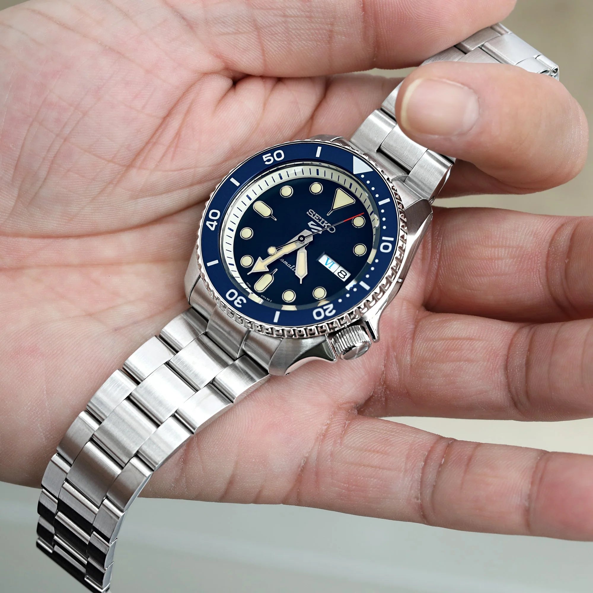 Seiko 5 dive watch with blue dial and stainless steel Super-O Boyer bracelet held in hand
