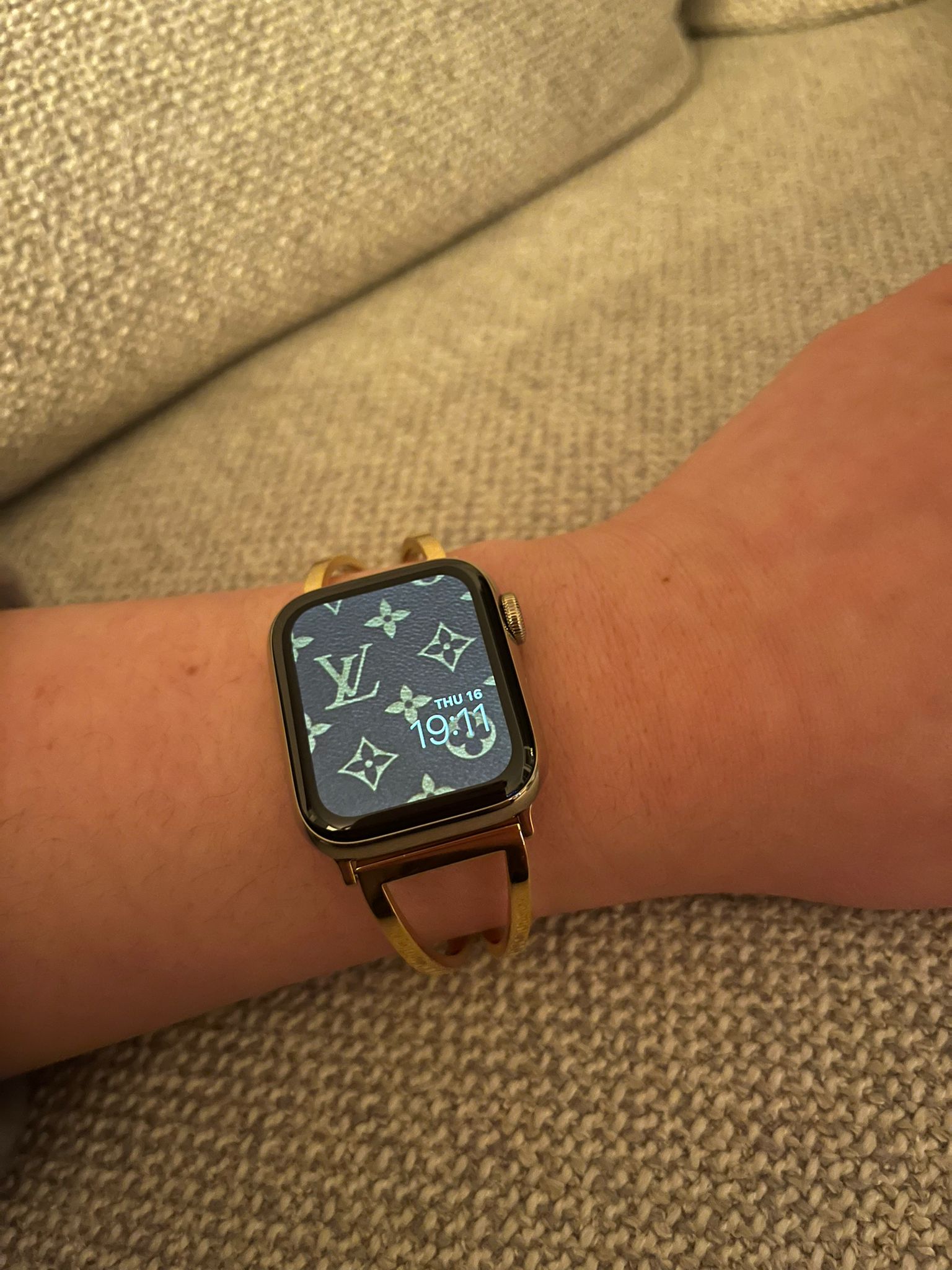 Luxury designer Apple Watch with gold case and nude leather band displaying monogram pattern on screen