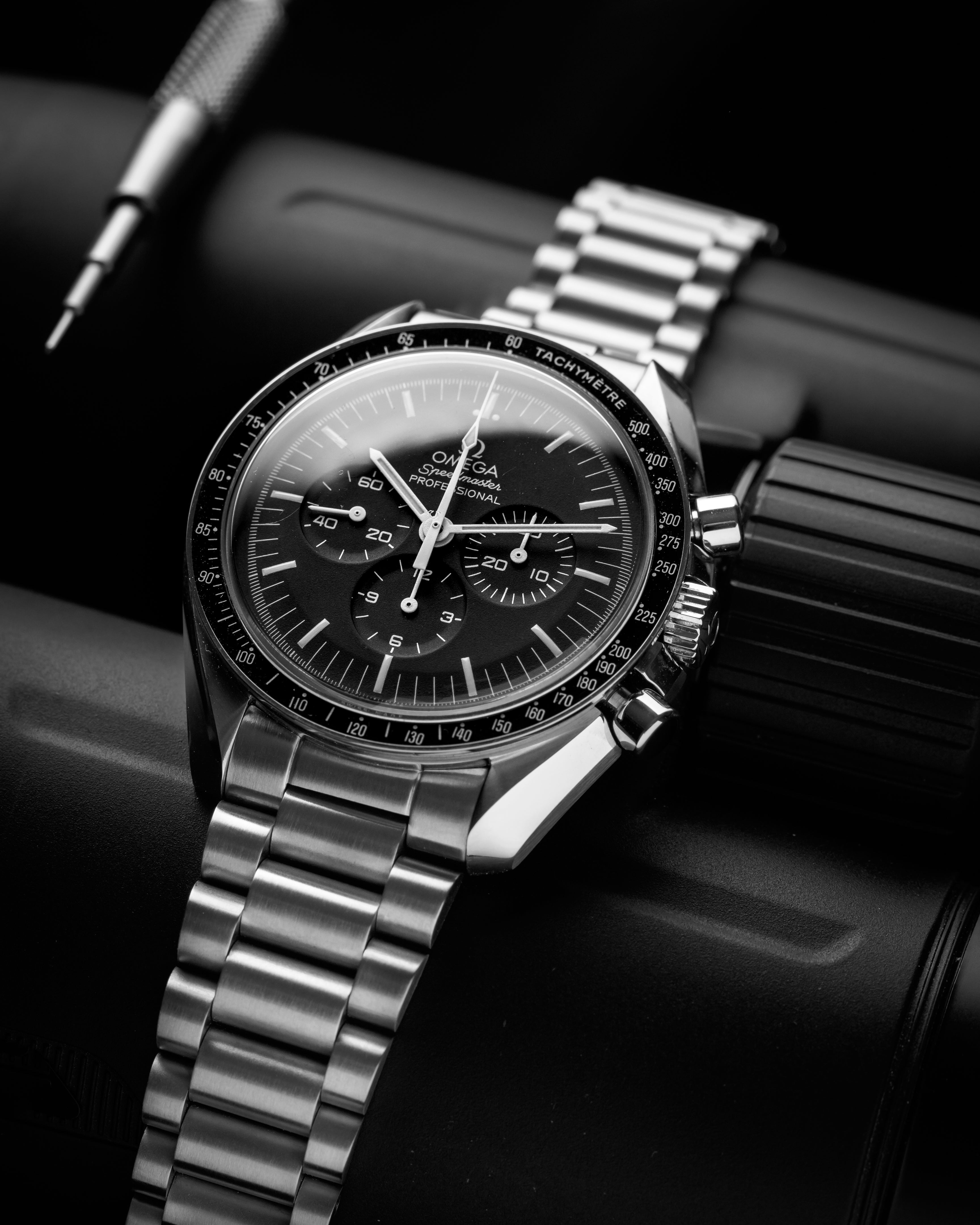 Omega Speedmaster Professional chronograph watch with steel bracelet and black dial displayed on black leather background