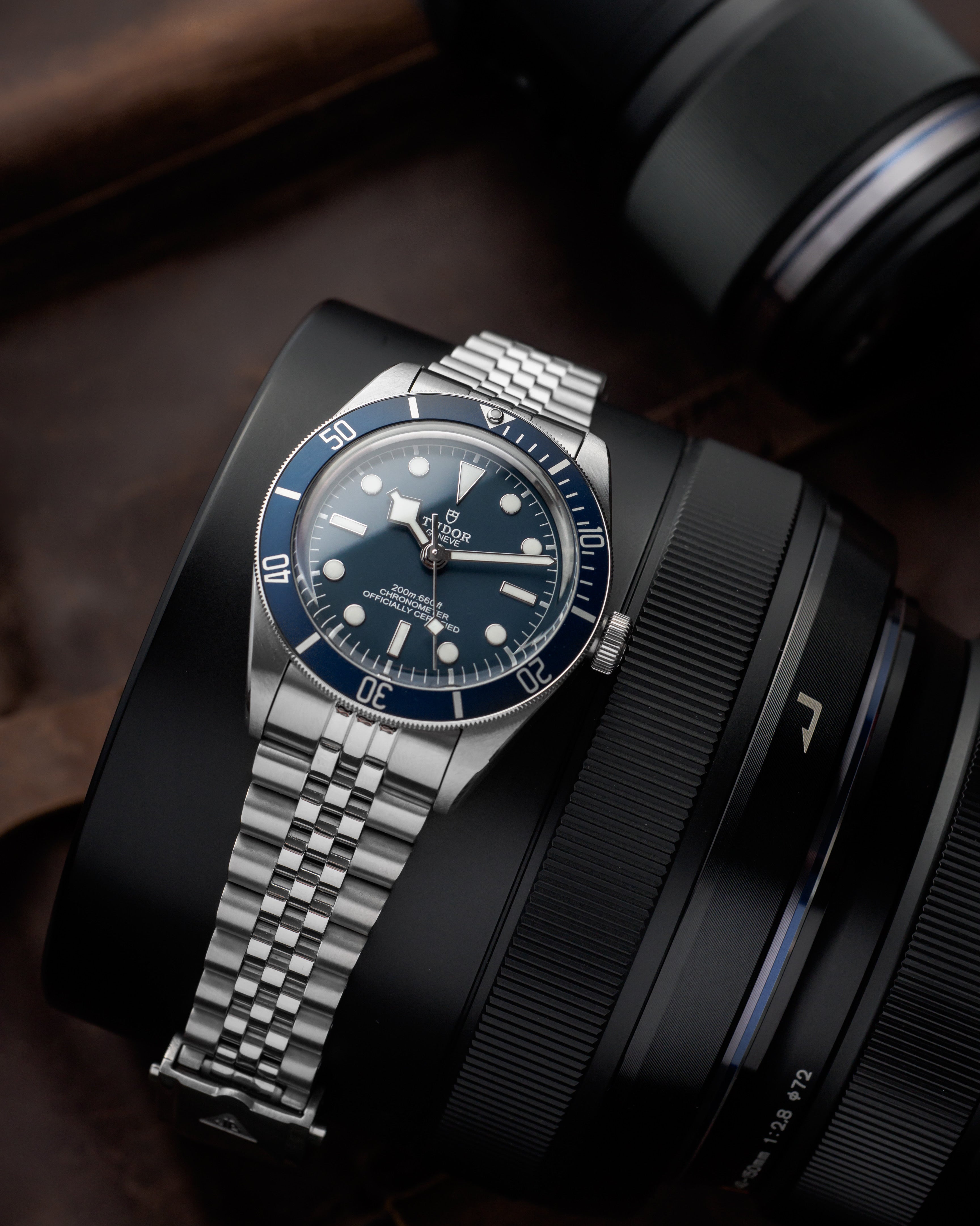Tudor Black Bay stainless steel dive watch with blue bezel and dial next to camera lens