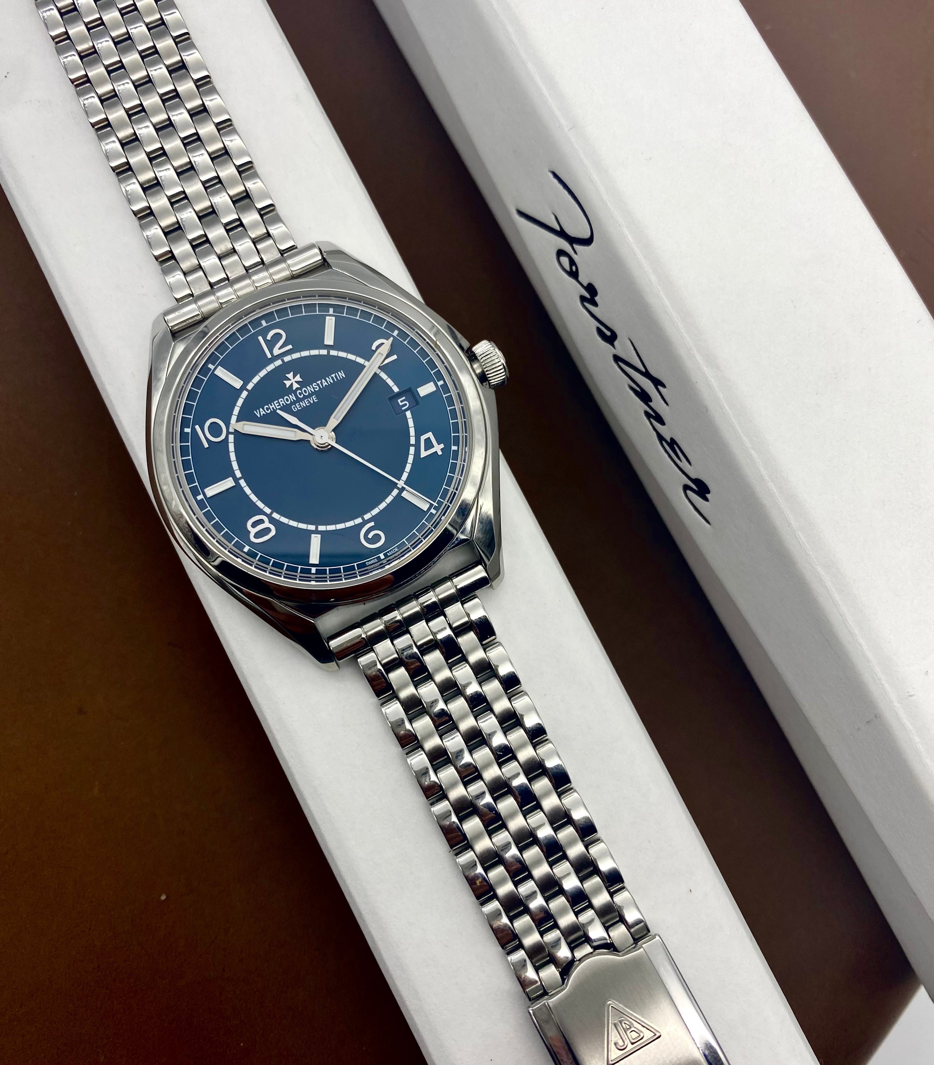 Stainless steel luxury watch with blue dial and silver bracelet in branded box packaging