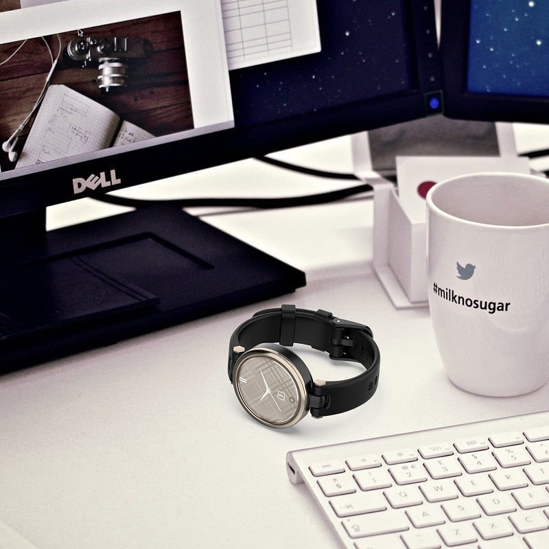 Black silicone smartwatch with round dial displayed on modern desk workspace with keyboard and coffee mug