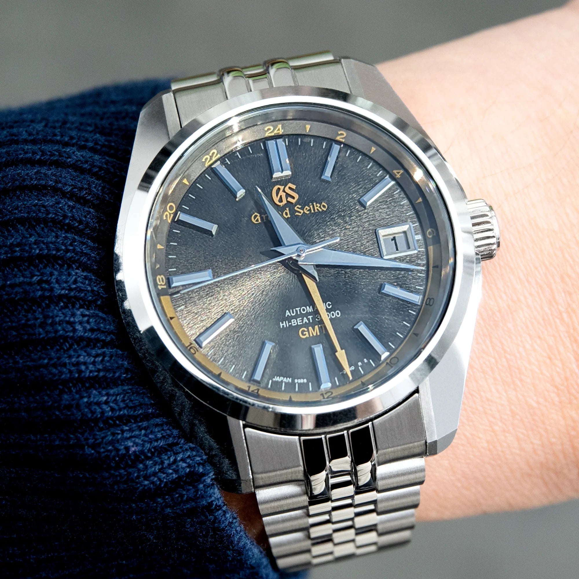 Grand Seiko automatic watch with charcoal dial, stainless steel bracelet, date window, and Hi-Beat 36000 movement on wrist