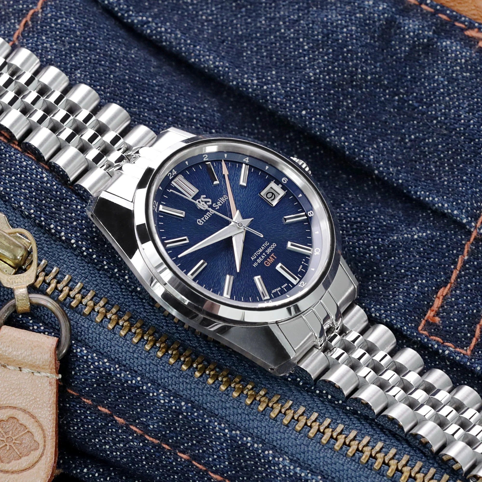 Stainless steel Super-J Louis bracelet 19mm with solid end links for Grand Seiko 44GS automatic watch on denim background