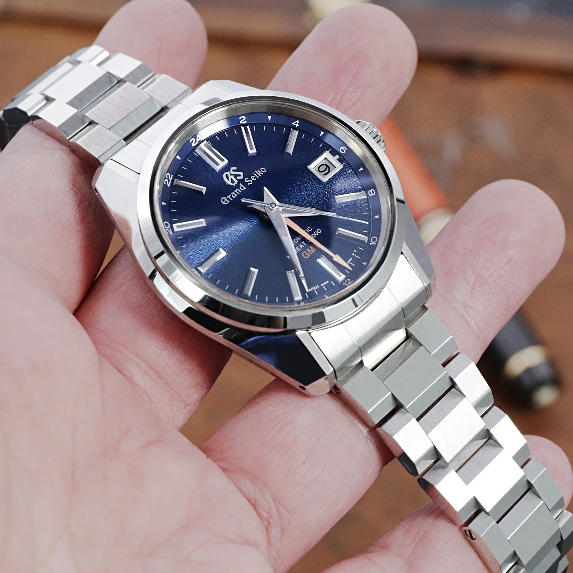 Grand Seiko 44GS watch with blue dial and stainless steel Hexad III bracelet held in hand